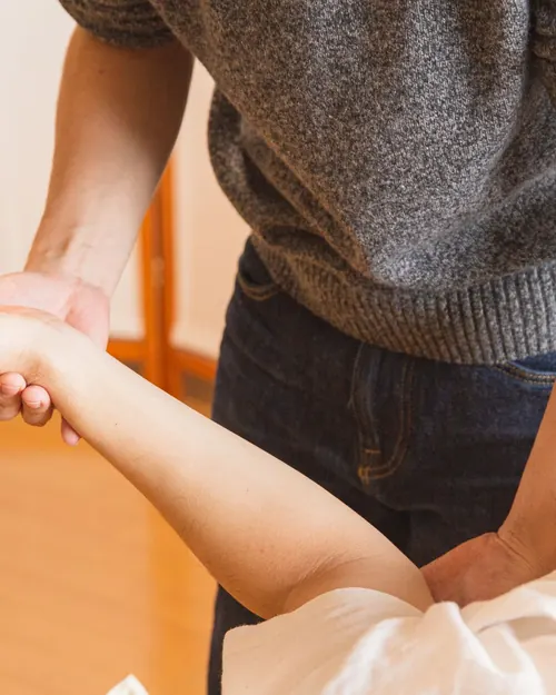Fisioterapeuta trabajando la movilidad de una mano en una sala con suelo de madera