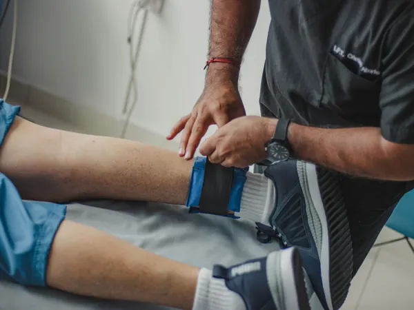 Fisioterapeuta ajustando una banda elástica en la rodilla de un paciente